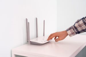 a hand push the power on button of the wifi router, internet connection equipment