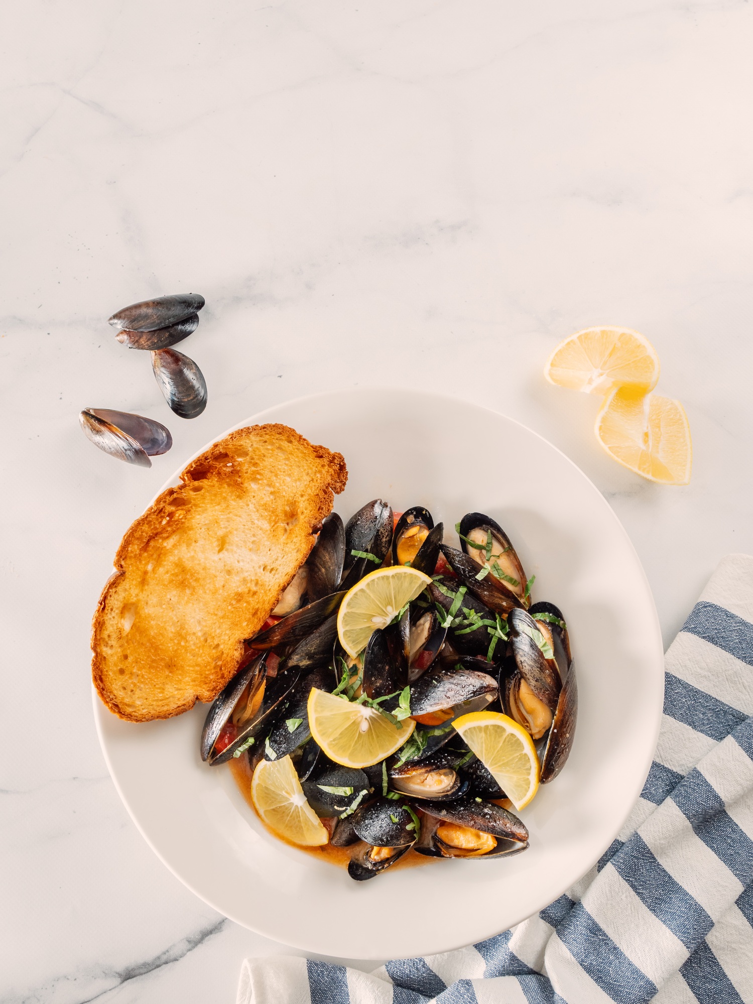 cooked mussels with lemon in white bowl