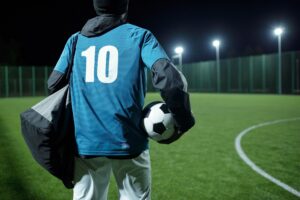 Rear view of football player with bag and soccer ball